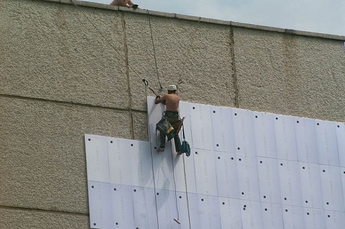 Промышленные альпинисты заняты утеплением фасада
